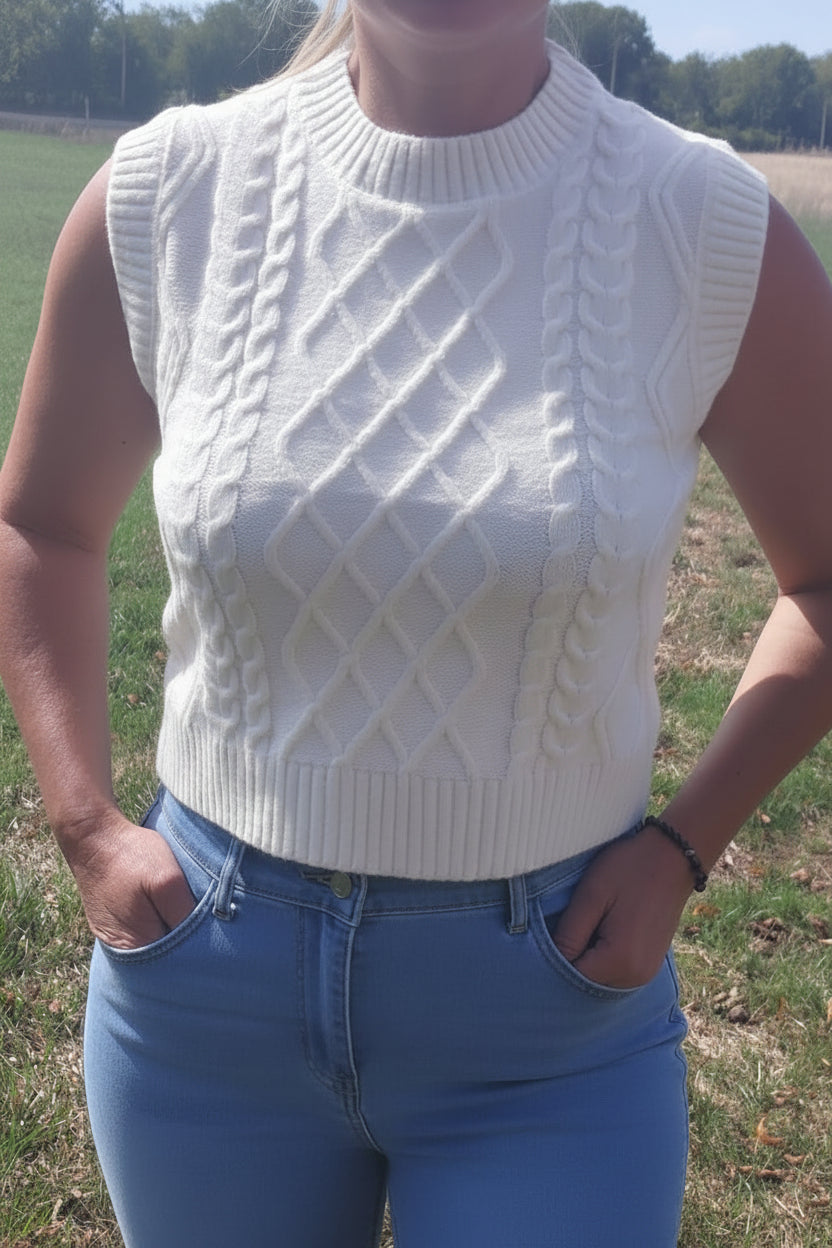 Pull sans manches col rond écru en tricot torsadé, porté avec jean bleu en extérieur